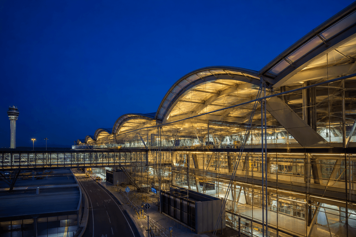 Night view of airport terminal softly glowing through ETFE roof