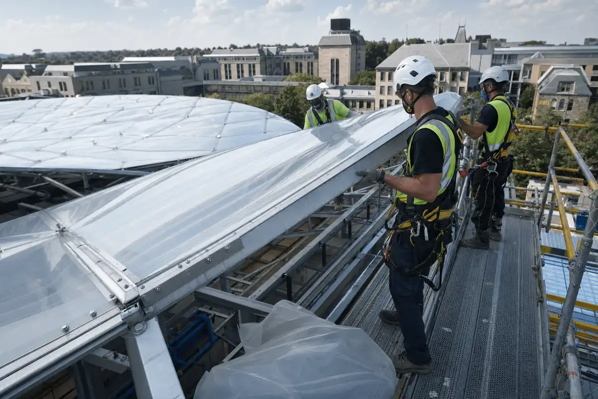 Construction crew installing ETFE modules on roof grid — College Campus ETFE Roofing