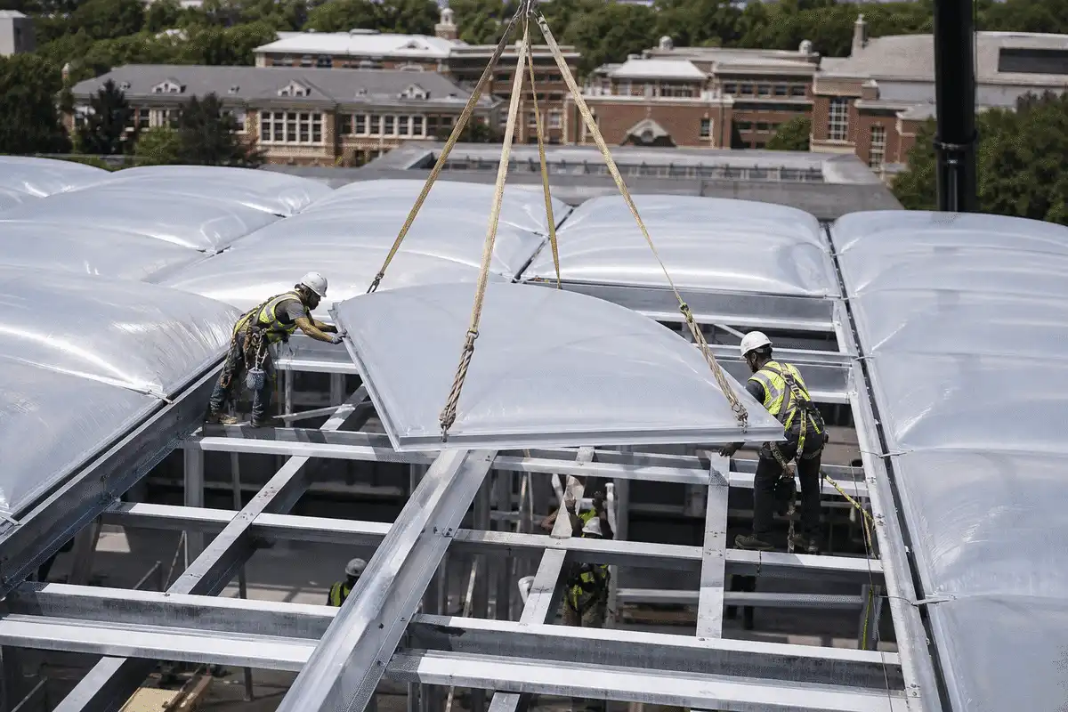 Construction crew installing ETFE cushion modules on a college roof grid — College Campus ETFE Roofing systems