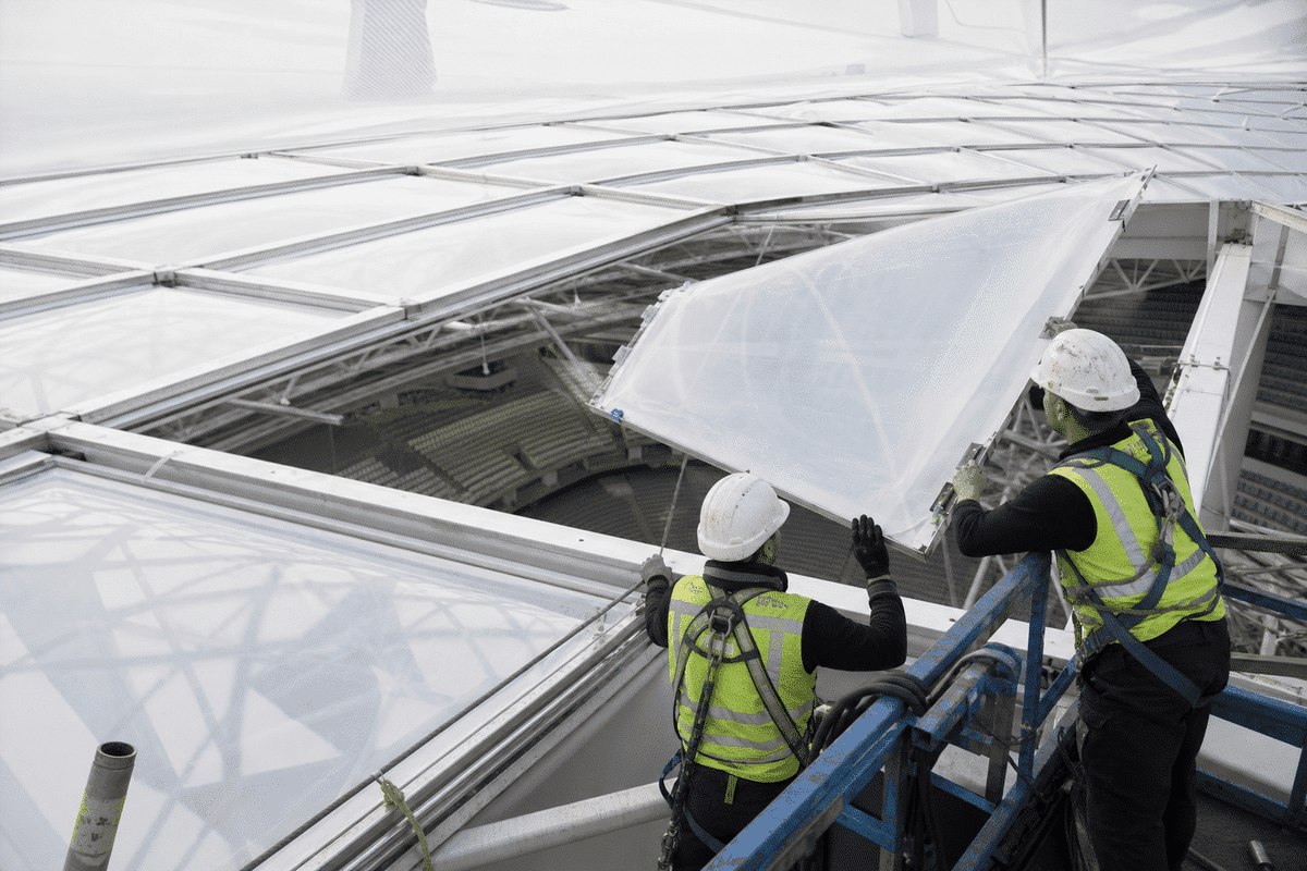 Construction crew installing ETFE modules on roof grid