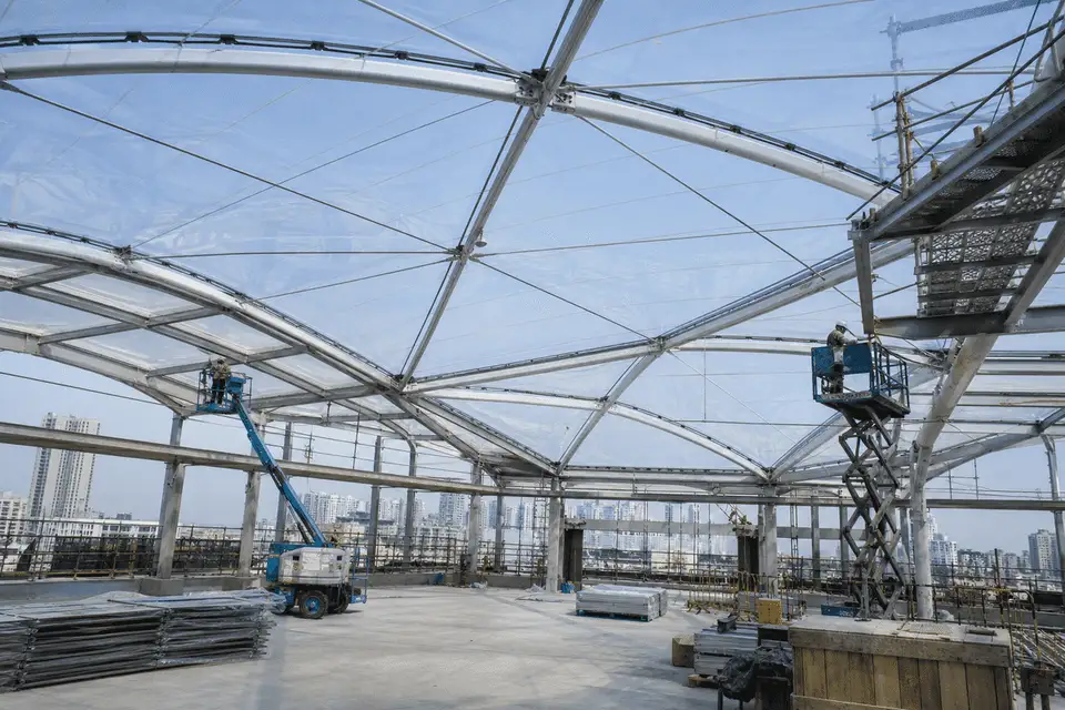 Construction crew installing ETFE cushion modules on a office building roof grid — Office Building ETFE Roofing systems