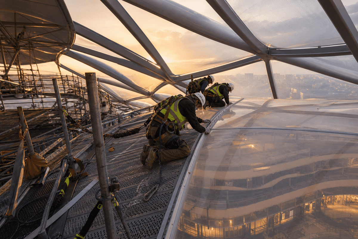 Construction crew installing ETFE cushion modules on a shopping mall roof grid