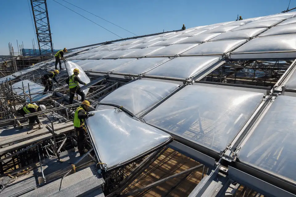 Construction crew installing ETFE cushion modules on a sportscomplex roof grid — Sports Complex ETFE Roofing systems