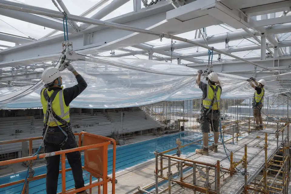 Construction crew installing ETFE cushion modules on a pool roof grid — Swimming Pool ETFE Roofing systems