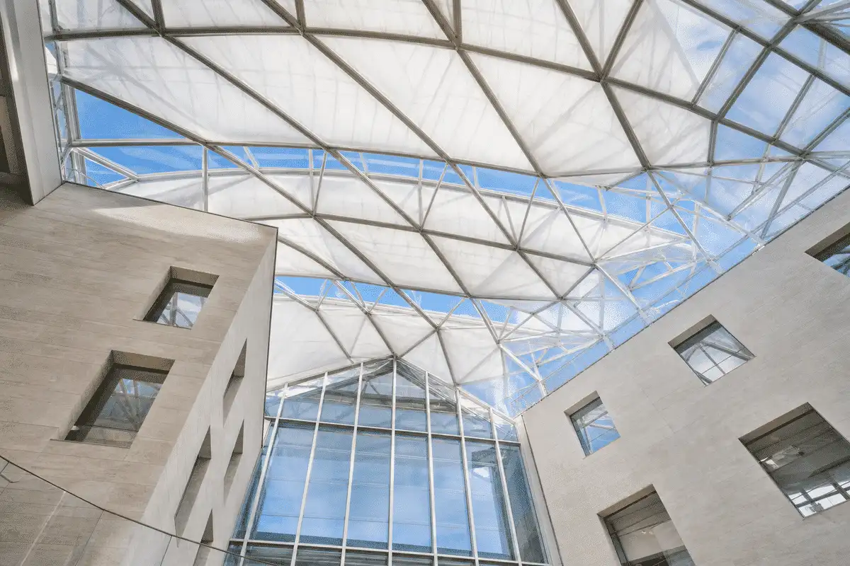 Interior view under luminous ETFE atrium with blue sky beyond — ETFE technical guide — ETFE technical guide