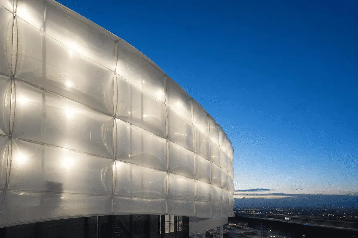 Translucent ETFE facade modules glowing under deep blue evening sky — ETFE technical guide